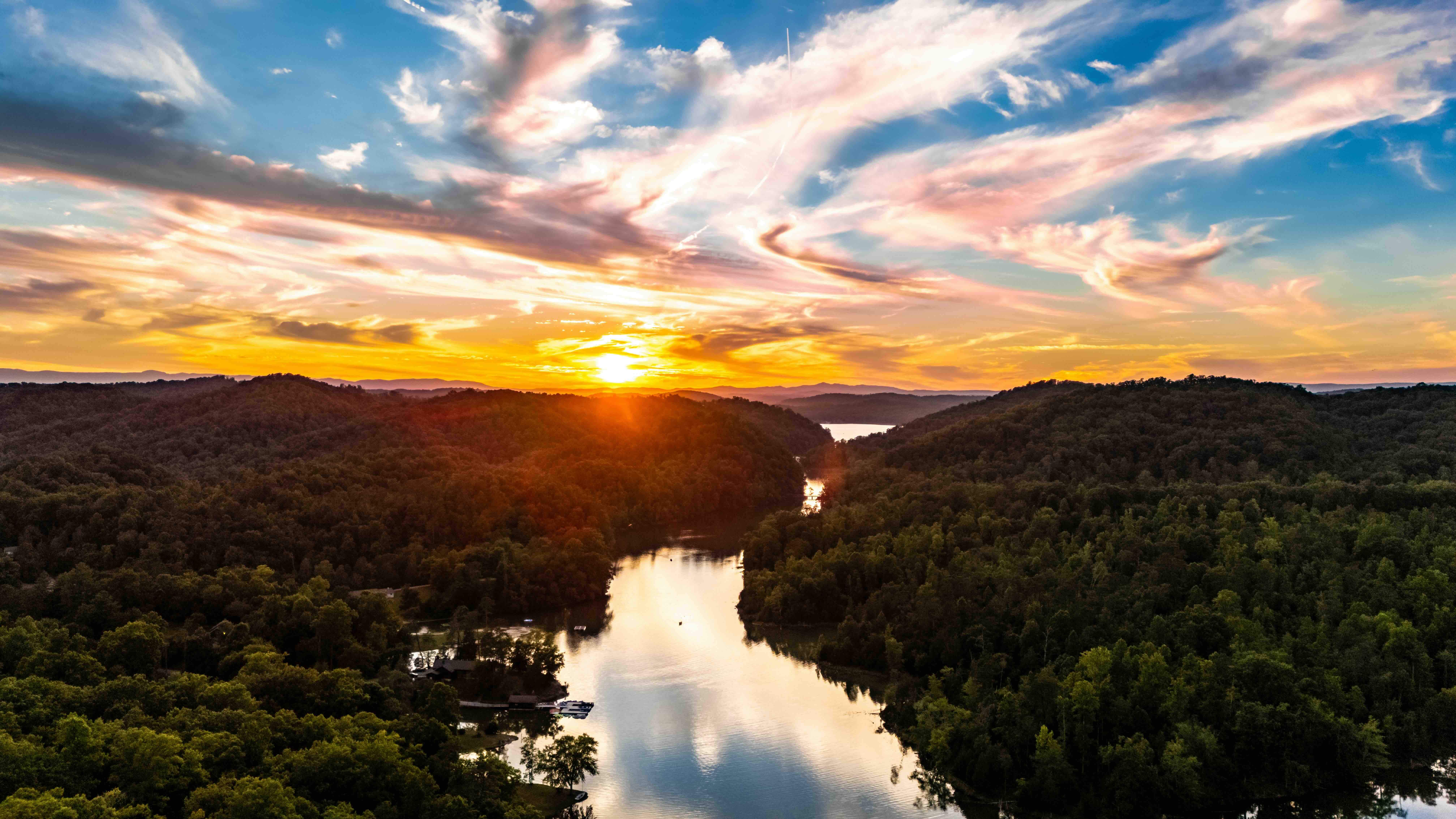 Sunset over a river winding through a forested landscape.