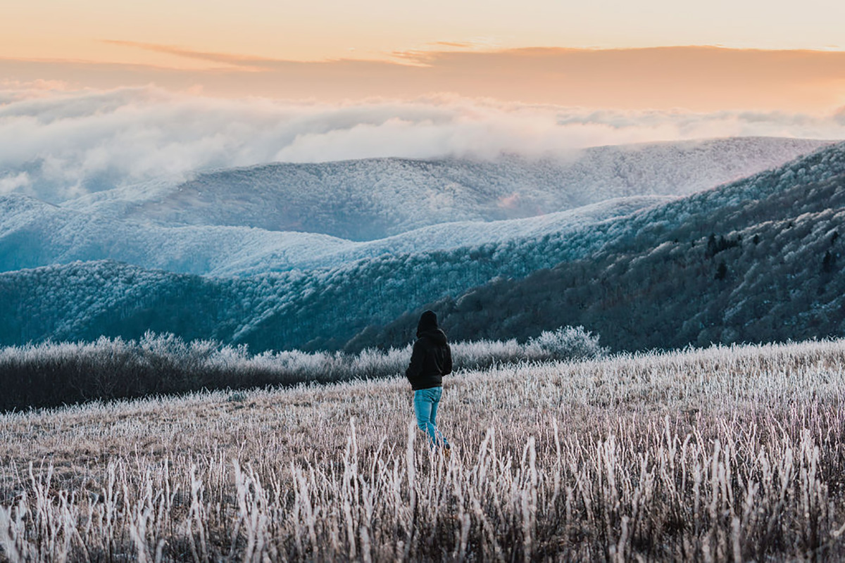 person in the middle of a field in the winter looking out onto mountains