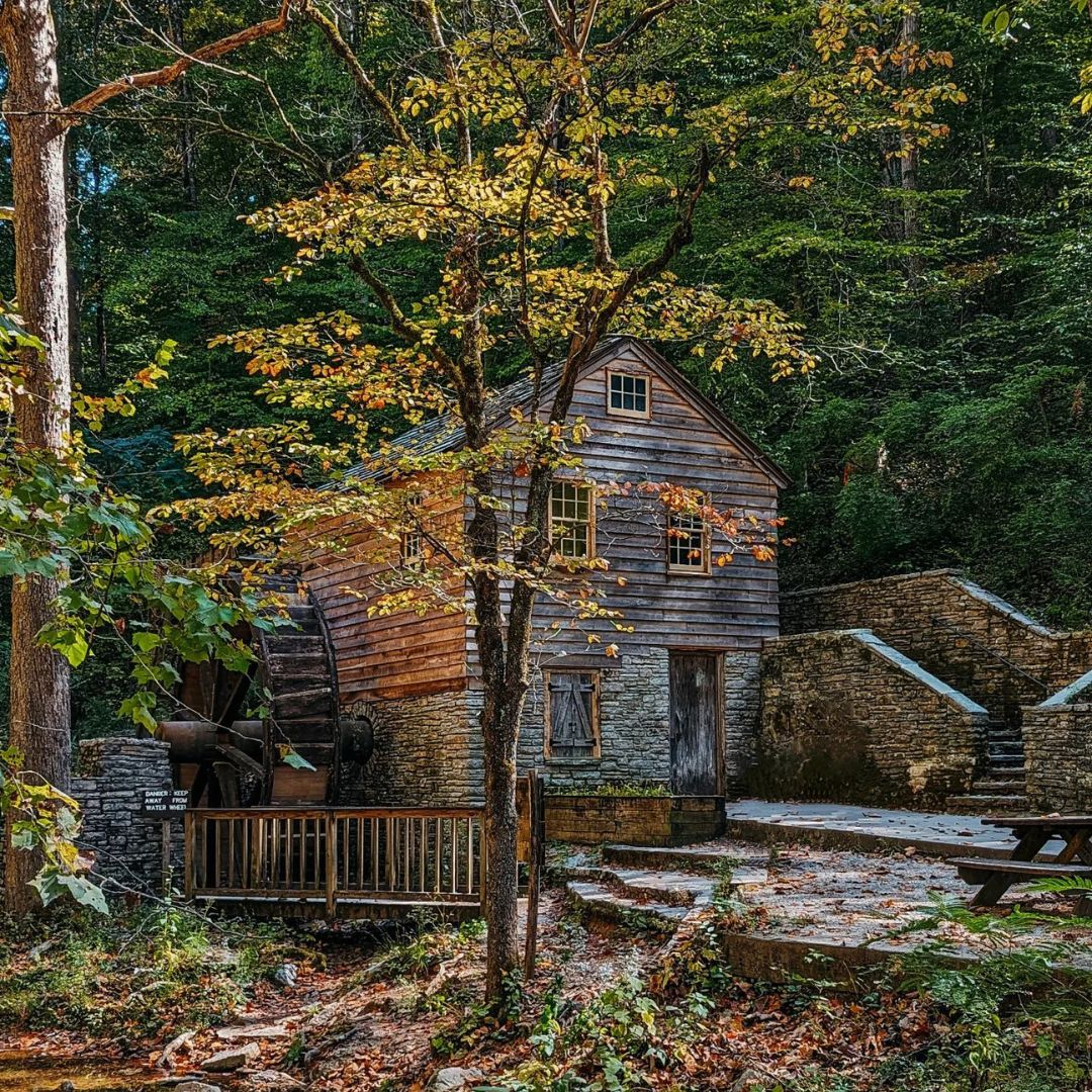 Old stone mill in a forest with autumn leaves.