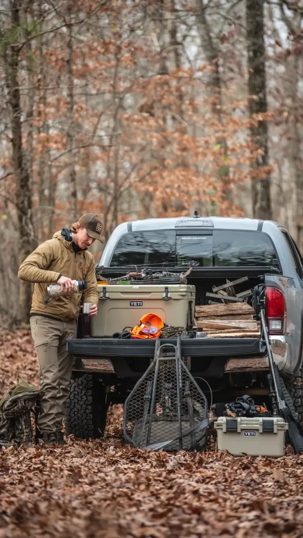 Truck camper parked in a wooded campsite.