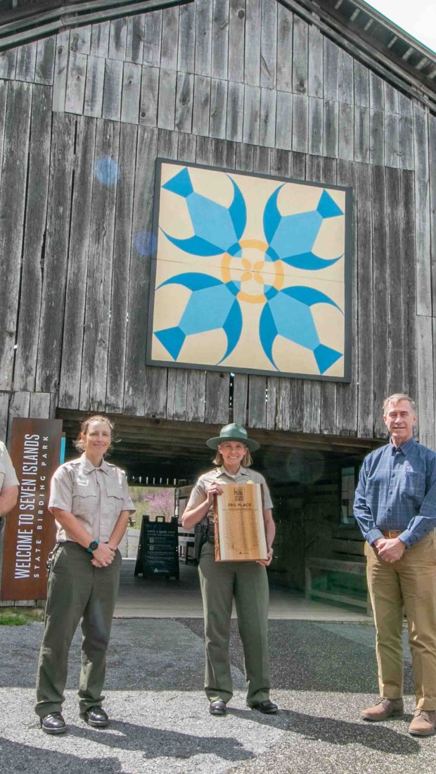 wooden brown barn with blue birds on it and people standing in front of it