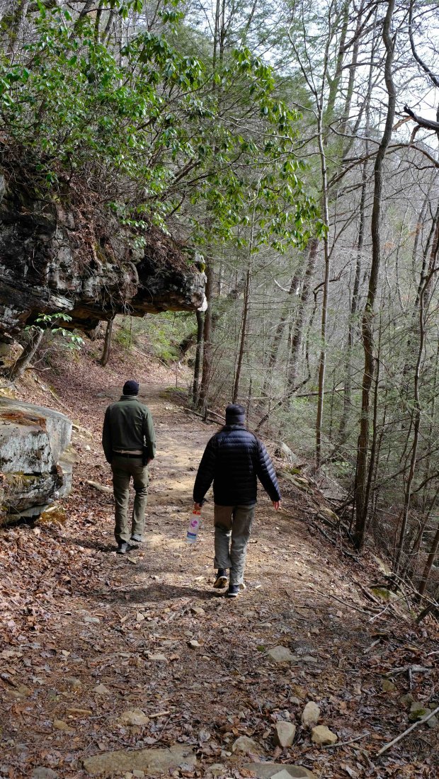 two people walking down a natural trail in the fall wearing winter jackets
