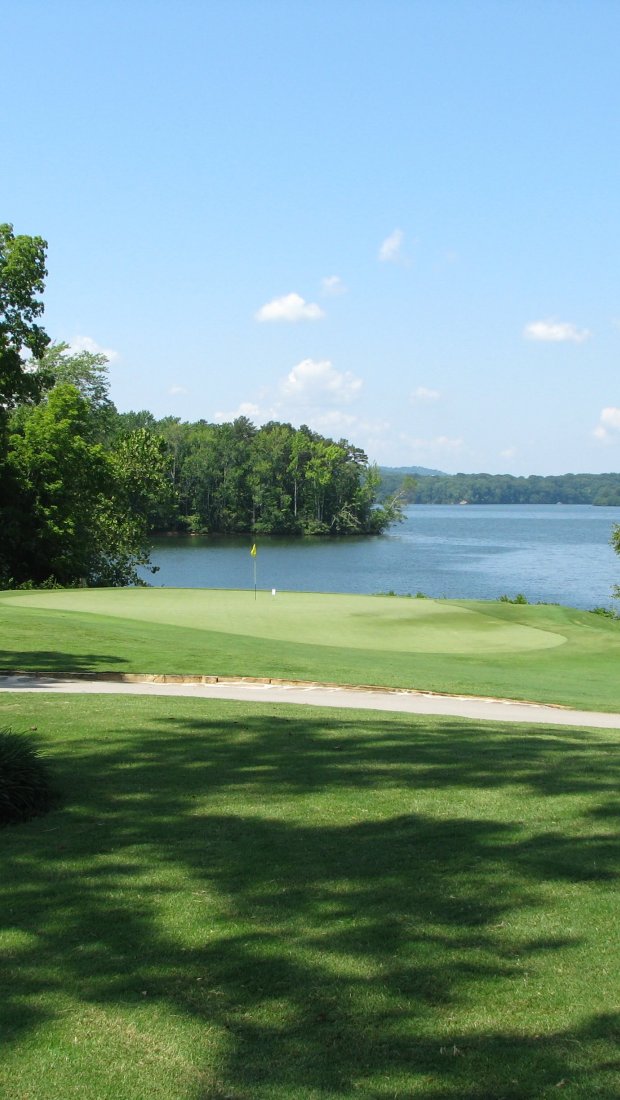 Golf course with lush greenery overlooking a large lake.