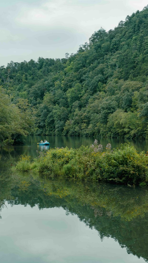 Serene lake surrounded by lush greenery with a small boat in the center.