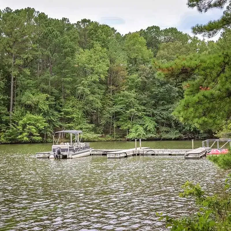 Boat dock extending into the lake with pontoon boats and covered slips.