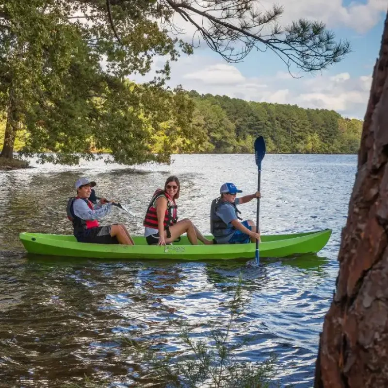 Group kayaking on the lake wearing life vests.