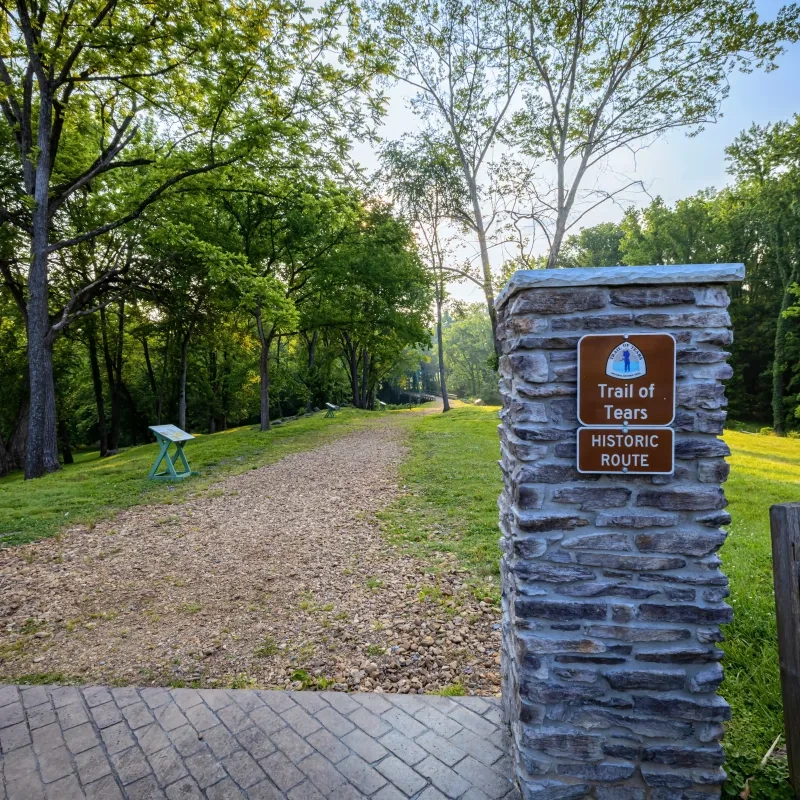Trail lined with trees and a stone sign reading "Trail of Tears Historic Route."