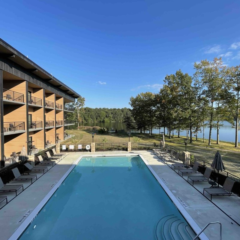 second story view of pool from a patio with the view of a lake in the background