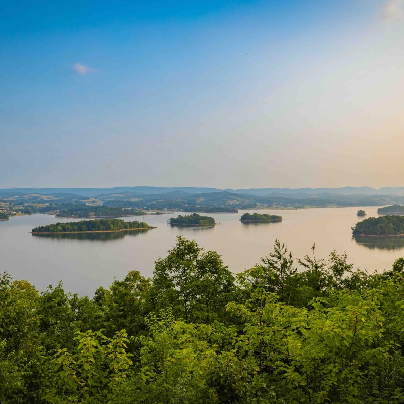 view of multiple small bodies of land on water with the sun beginning to set