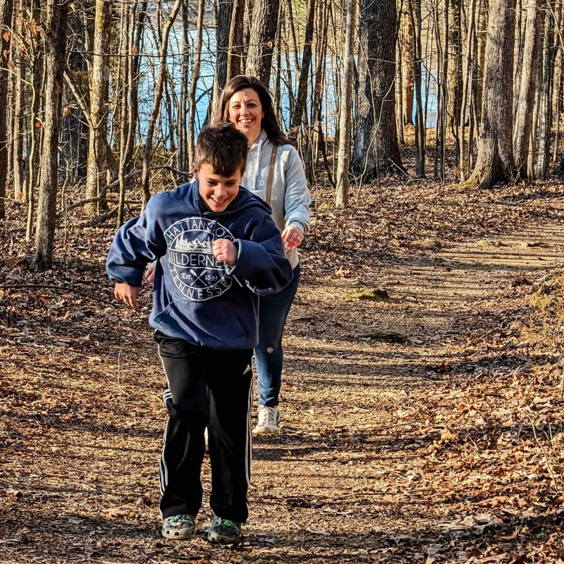 boy and woman walking down a trail in the fall