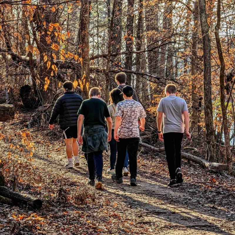 group of boys walking down a natural trail with a woman