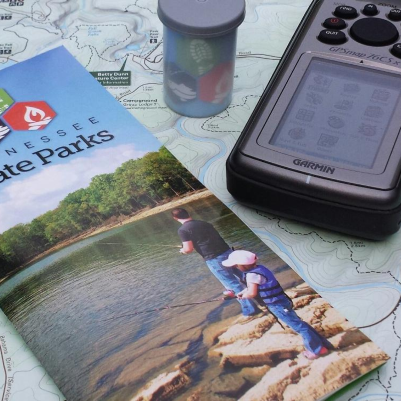 Travel guidebook, GPS device, and cup on a map.