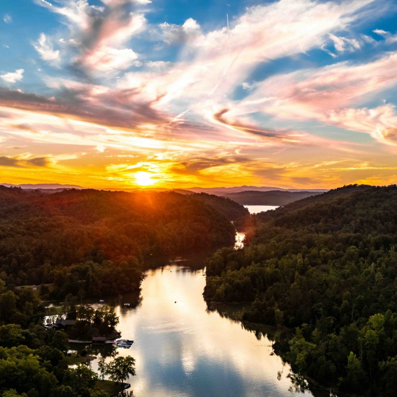 Sunset over a river winding through a forested landscape.