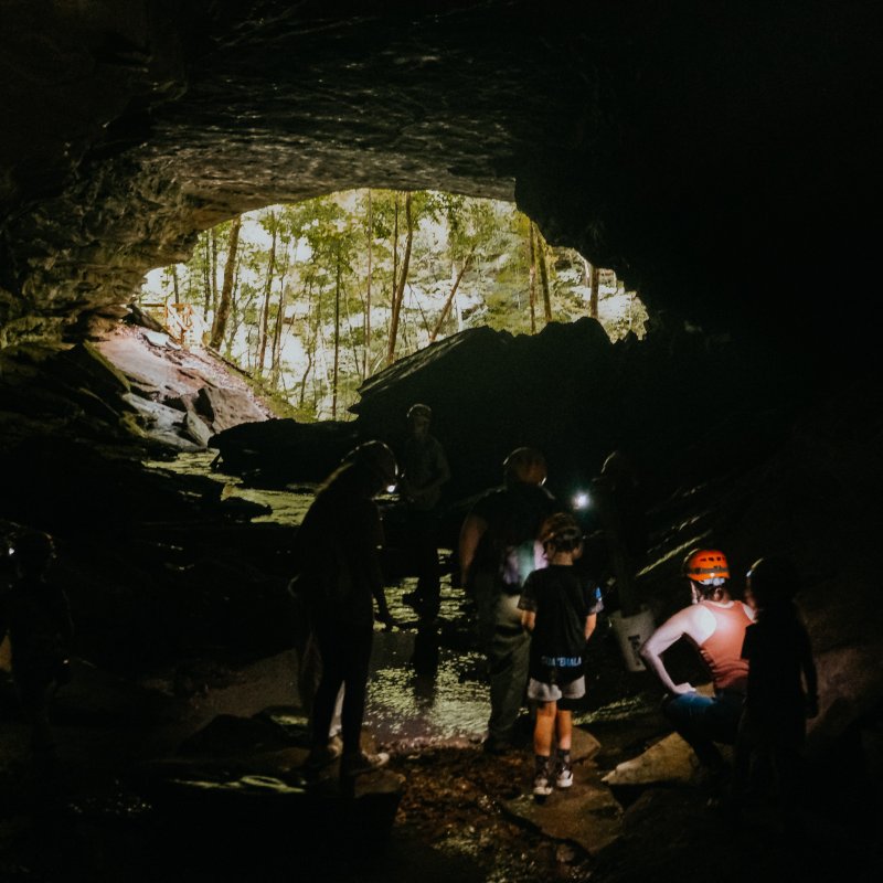 Group of people exploring a dimly lit cave with headlamps.