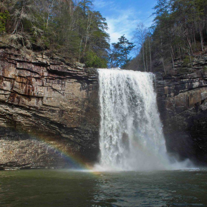 Waterfall cascading over a cliff with a rainbow at the base.