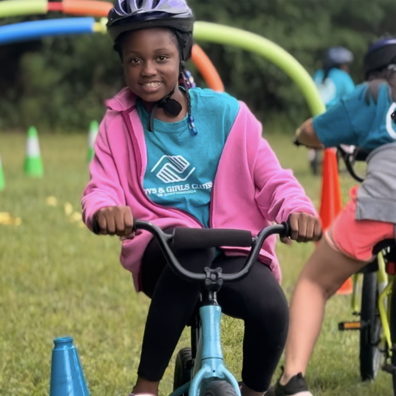 Children biking through an obstacle course with colorful cones.