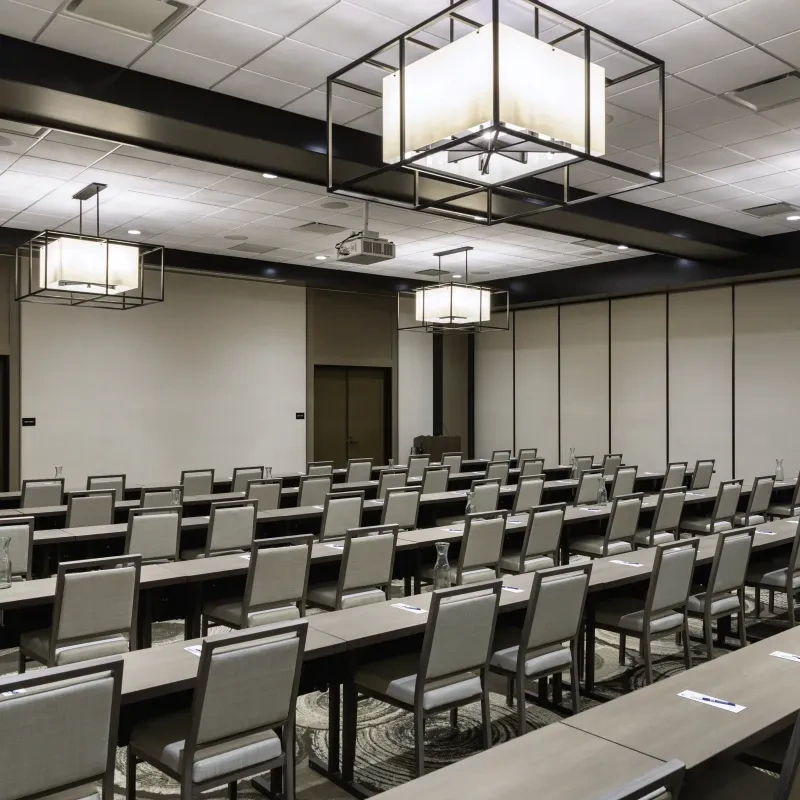 A large ballroom set u with long tables and chairs for a corporate meeting