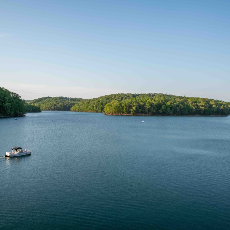Small boat on a serene lake surrounded by lush green hills.