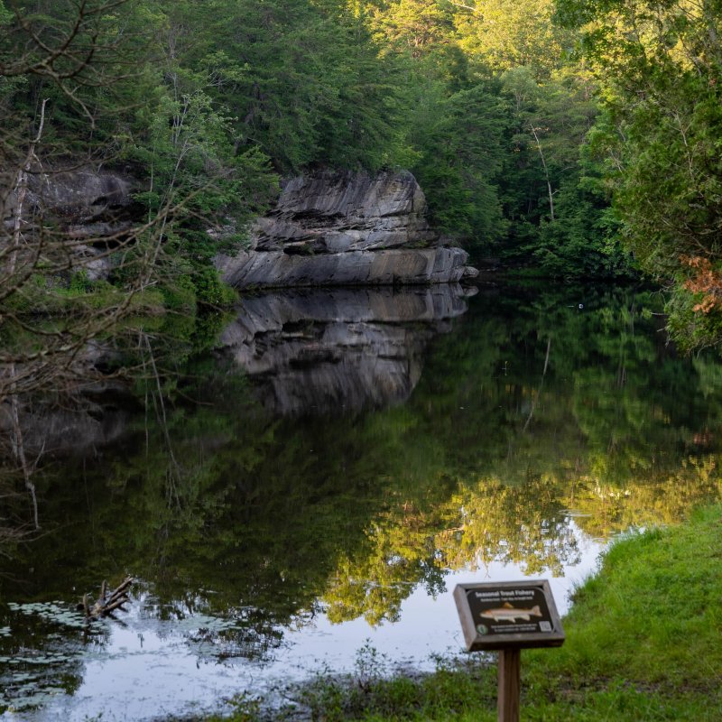 Serene riverbank with large rock formations and an information sign.