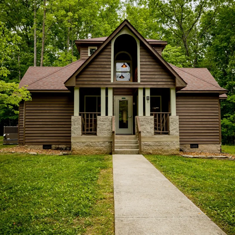 Brown wooden house with a central pathway and lush greenery.