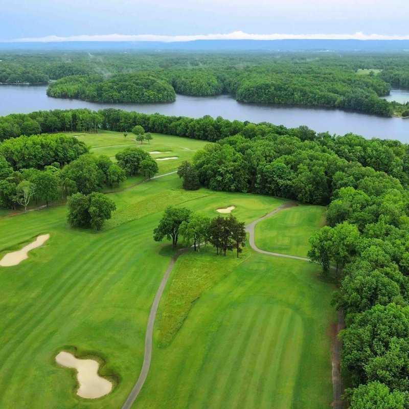 Aerial view of a lush golf course surrounded by a large river.