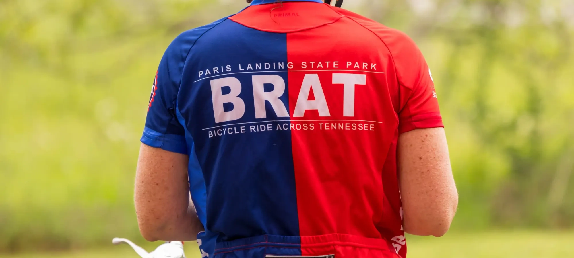 Cyclist in red and blue kit with helmet, outdoors.