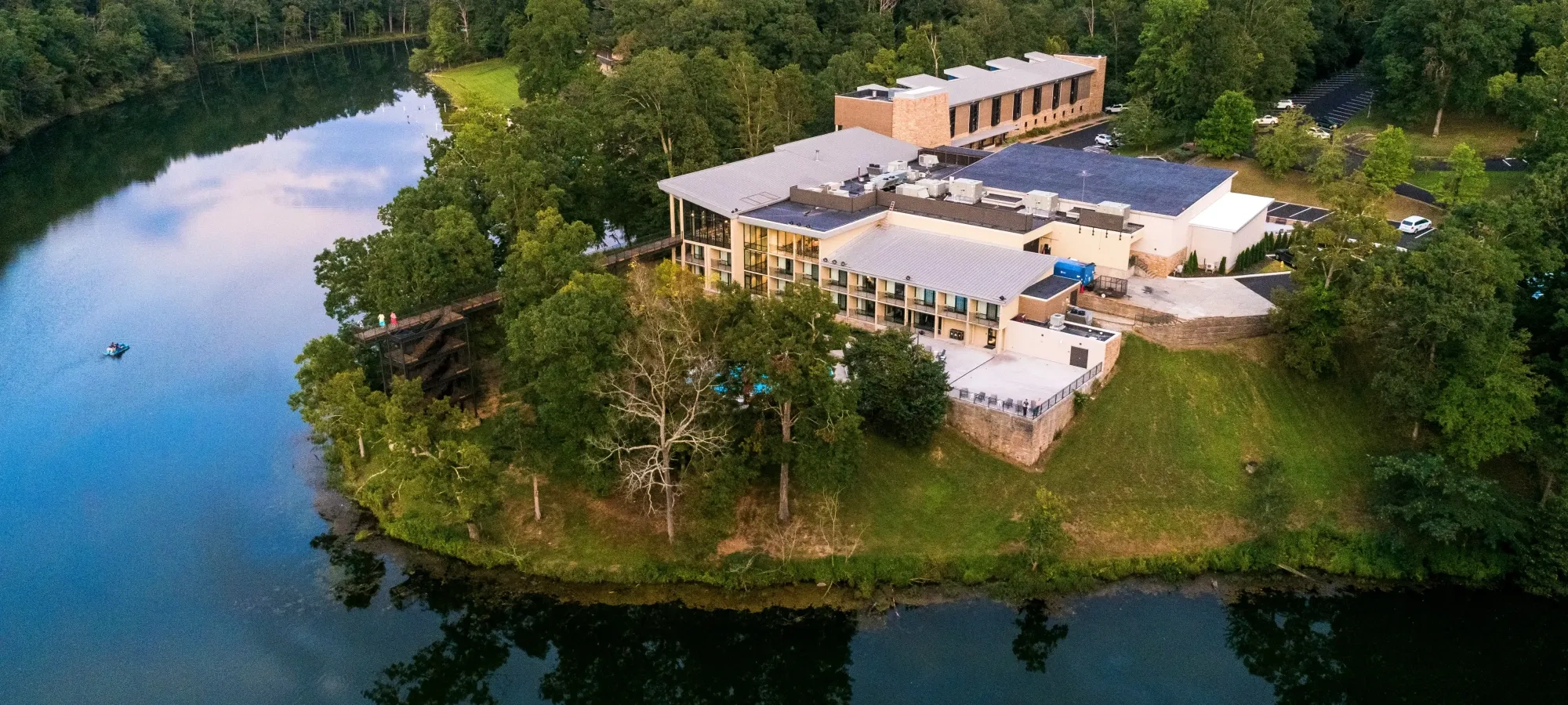 Aerial view of a riverside building surrounded by lush green forest.