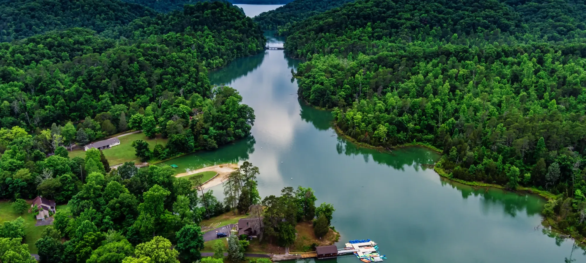 River winding through lush green hills under cloudy sky.