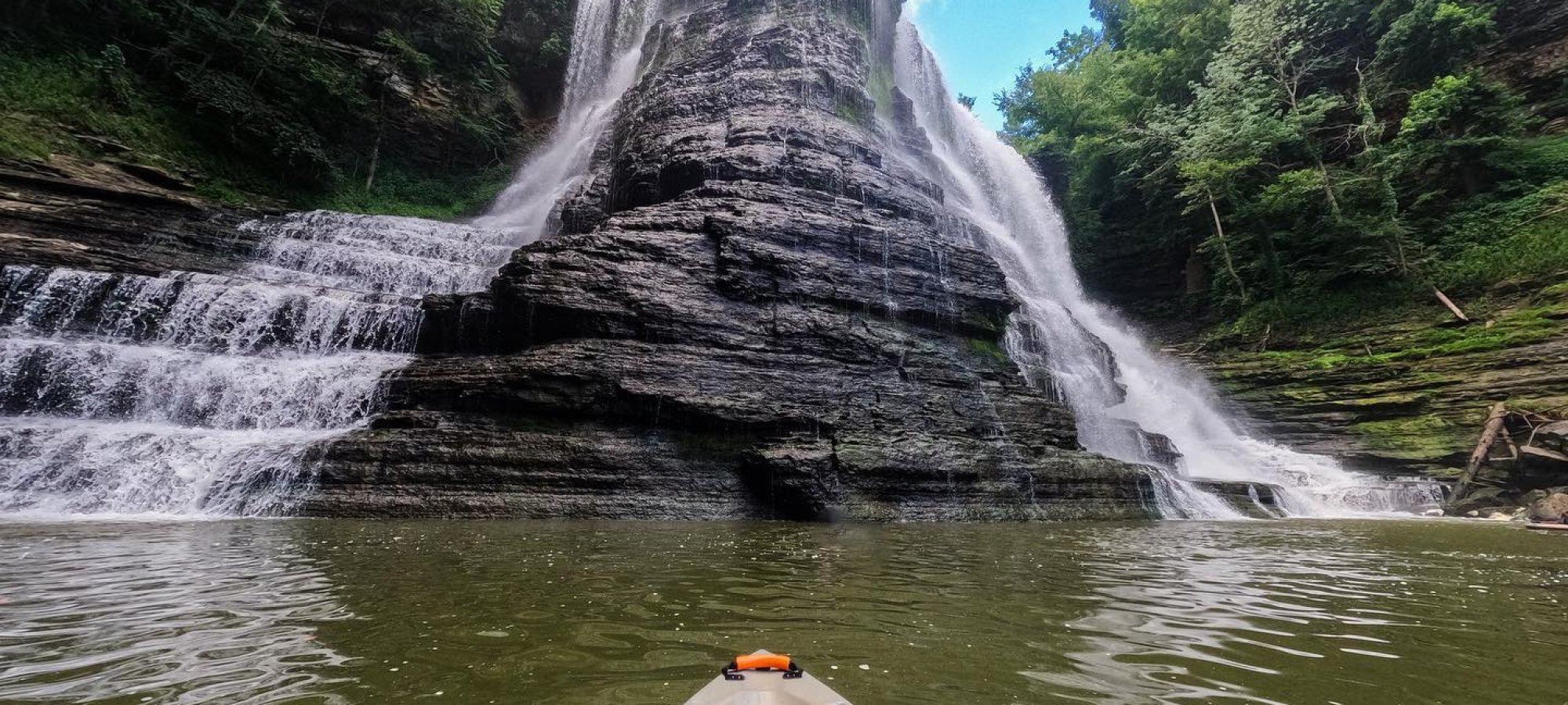 view of looking up a waterfall from a kayak on the water