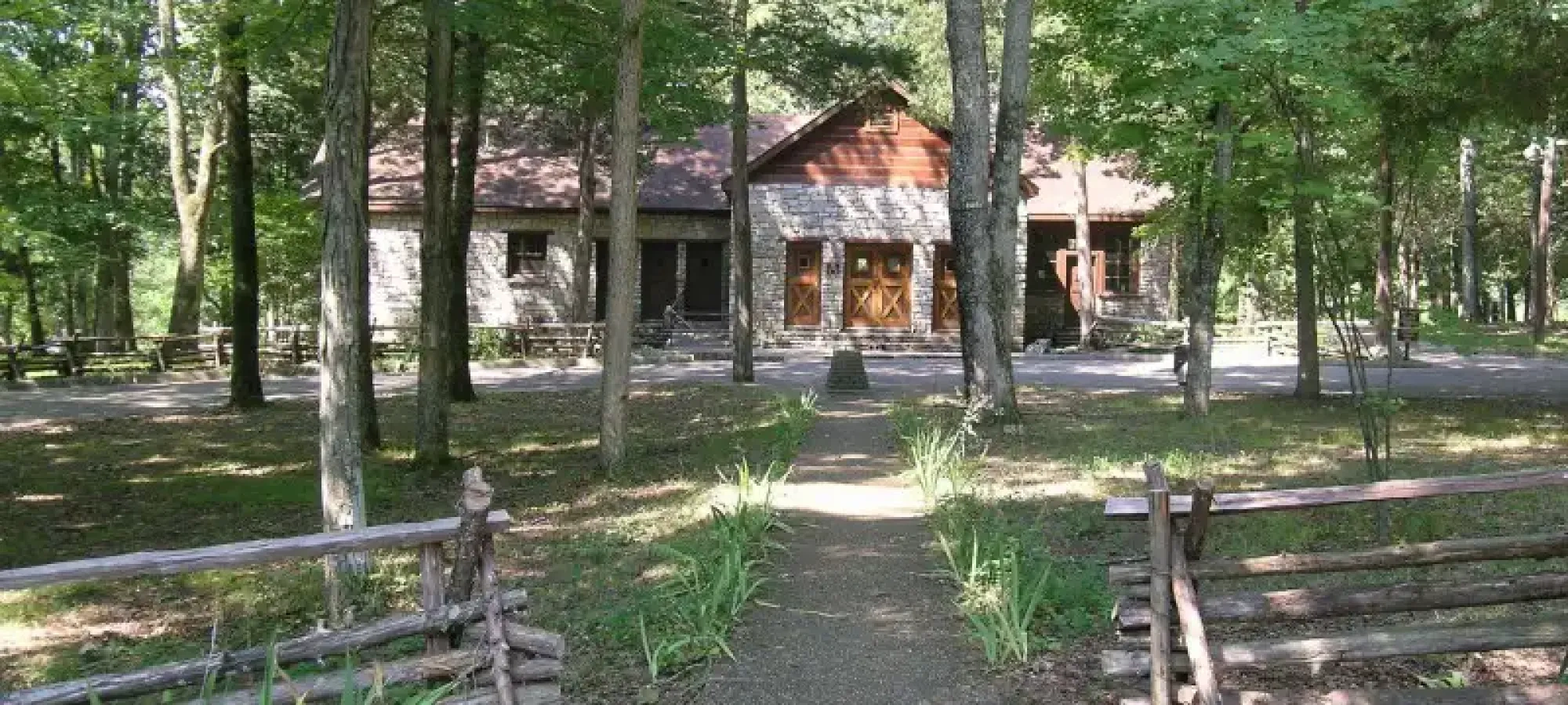 Cabin tucked back in the trees with a gravel walkway.