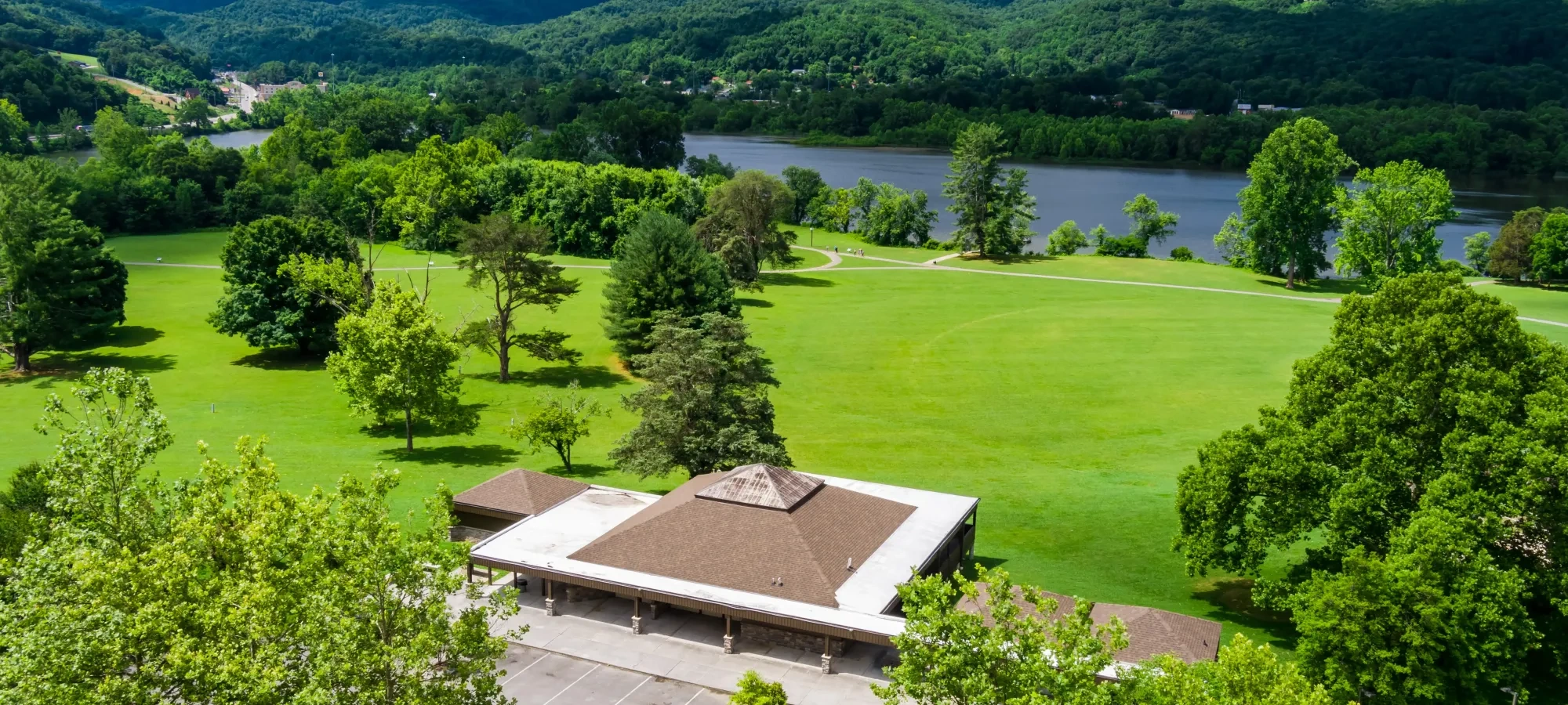 Building with parking, surrounded by lush greenery and distant mountains.