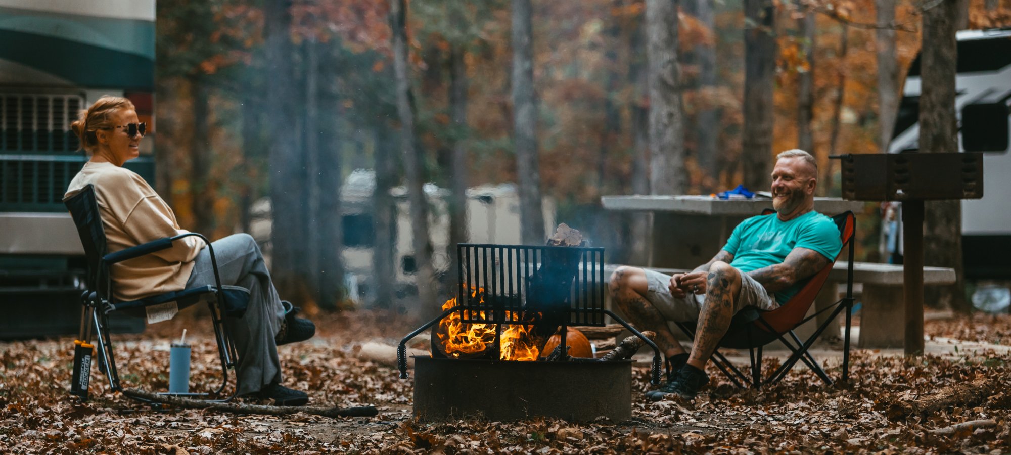 two man camping in the fall with a camp fire burning