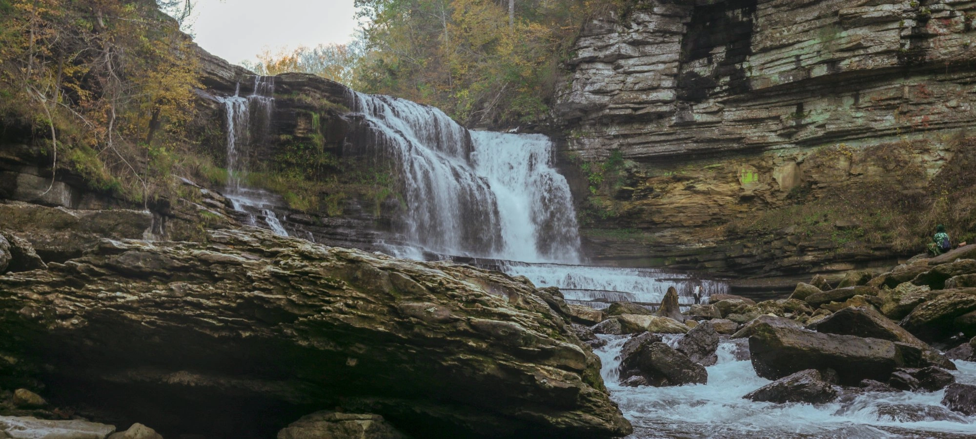 Waterfall cascading over rocky cliffs surrounded by trees.