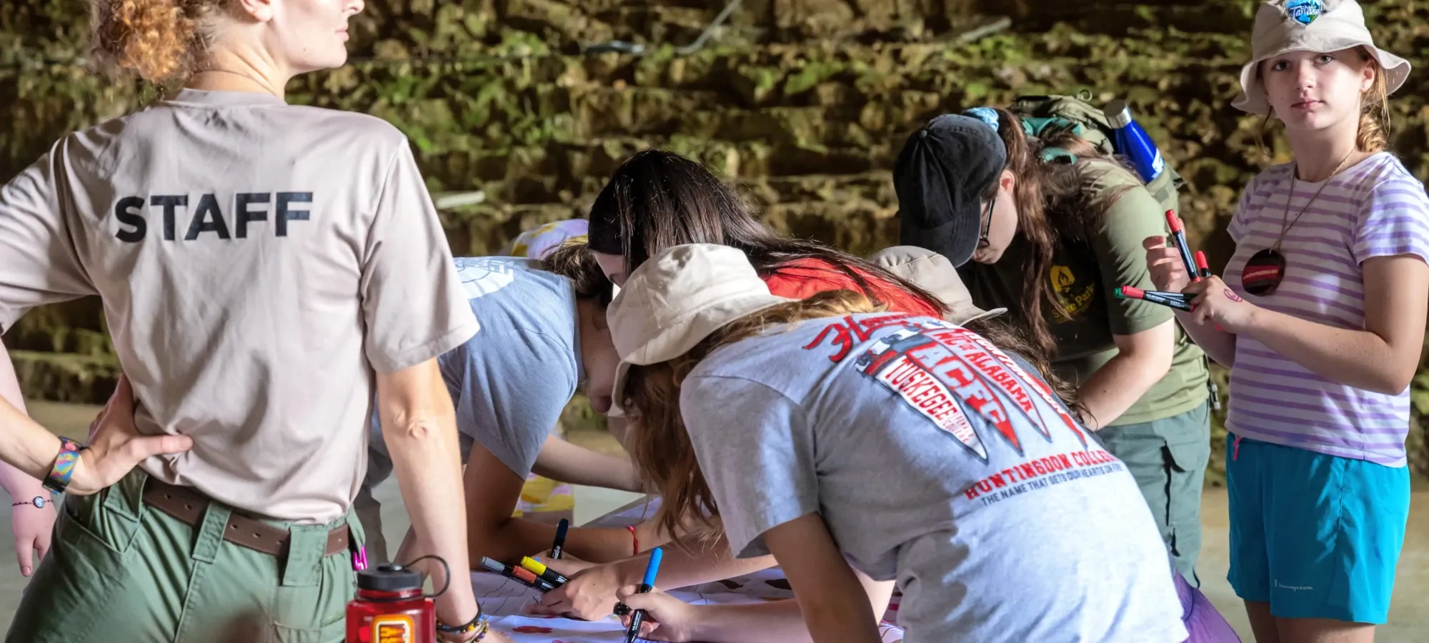 Group of people engaged in a drawing activity outdoors.