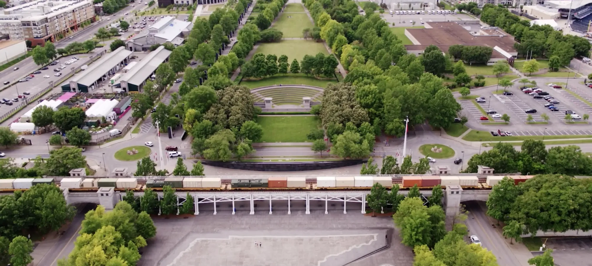 Aerial view of a city park with train tracks and surrounding buildings.