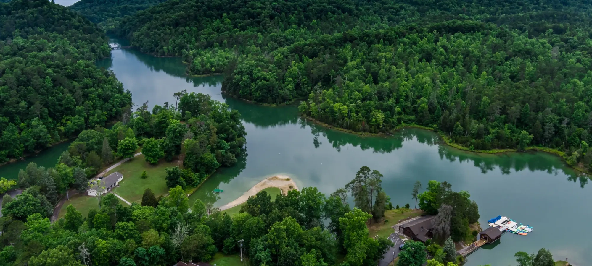 Lush green hills and river with houses nestled among trees.