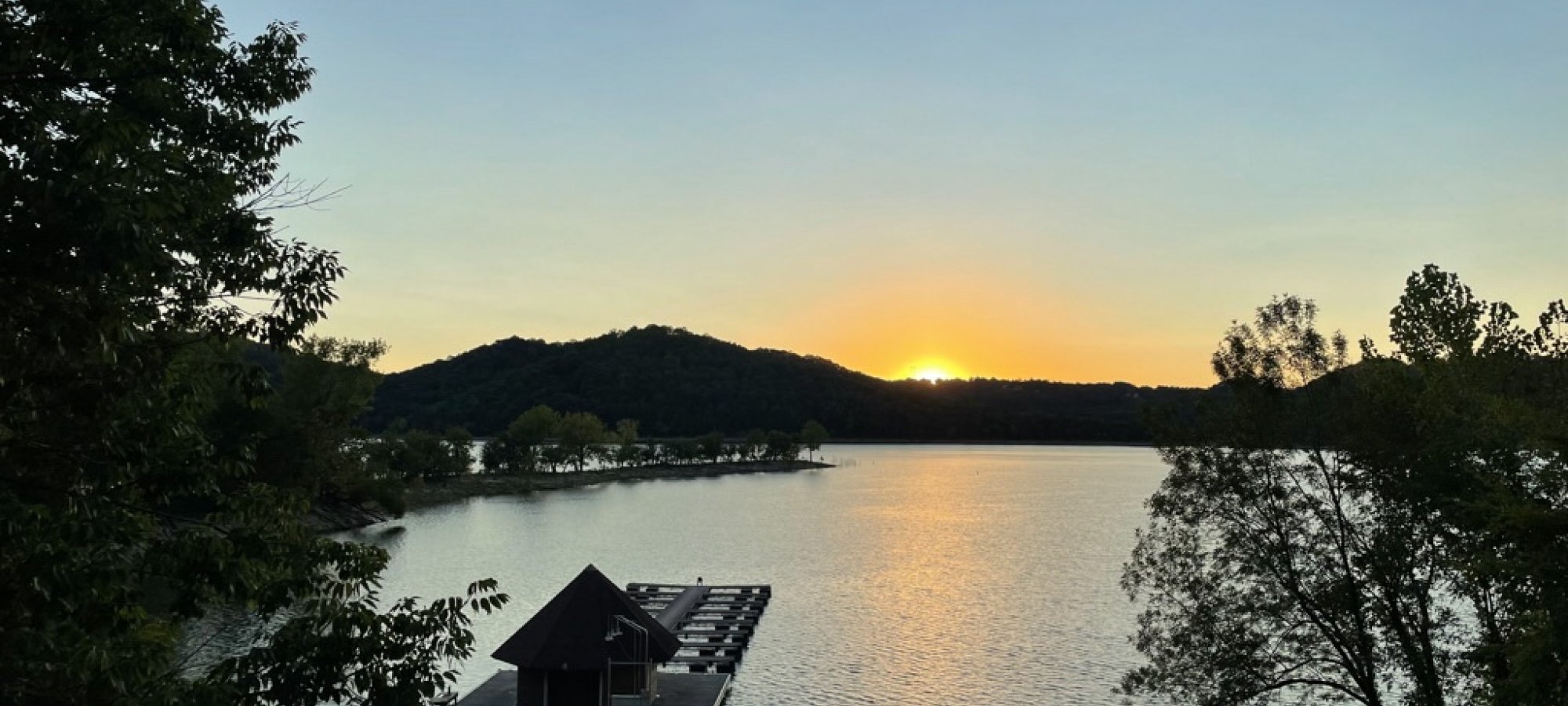 landscape view of the lake and the dock on the shore at sunset