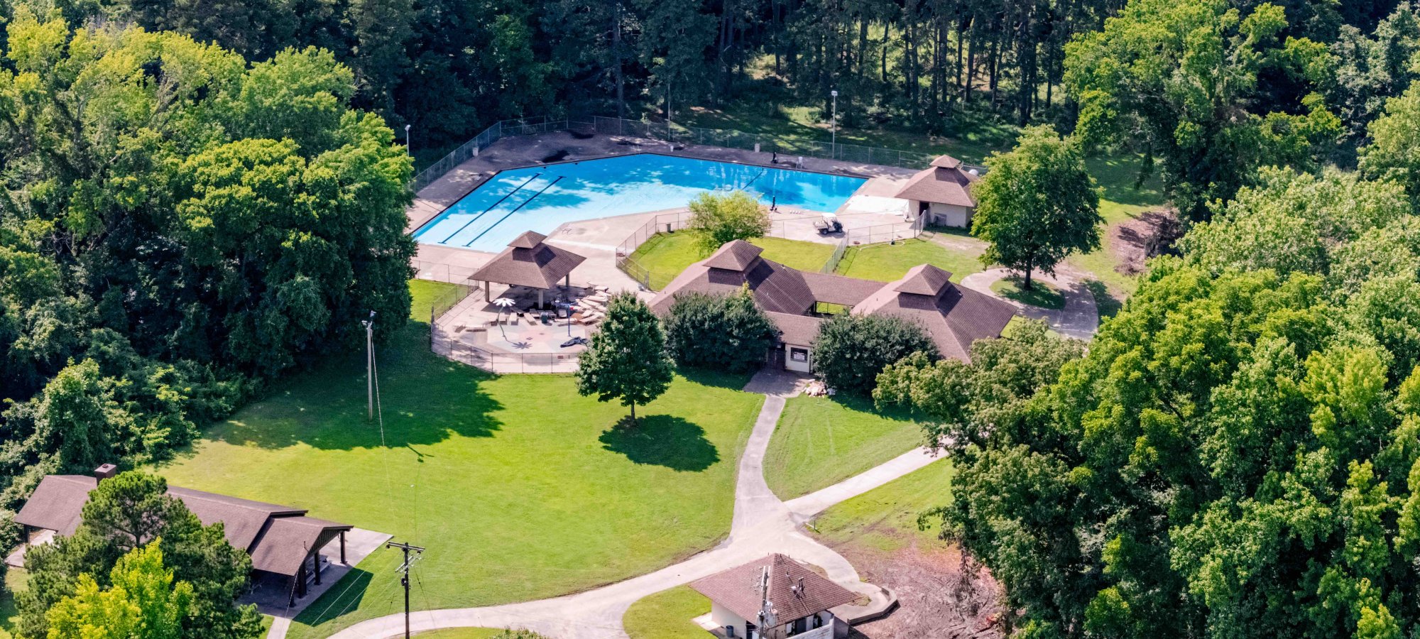 photo taken in the sky of the pool, several buildings, and shelters