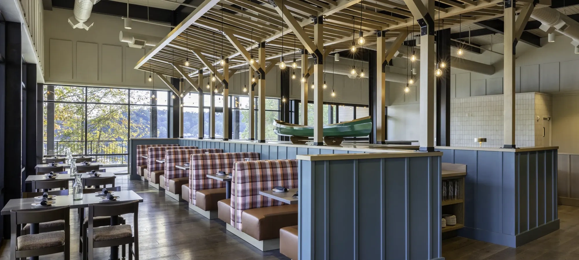 Inside a restaurant with wooden aesthetic, wooden tables and booths, and a canoe in the middle of the room raised up