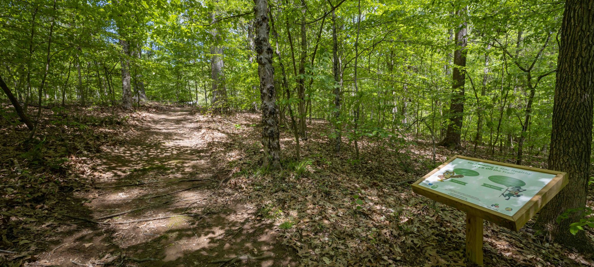 view of natural trail in forest with a education panel on the right