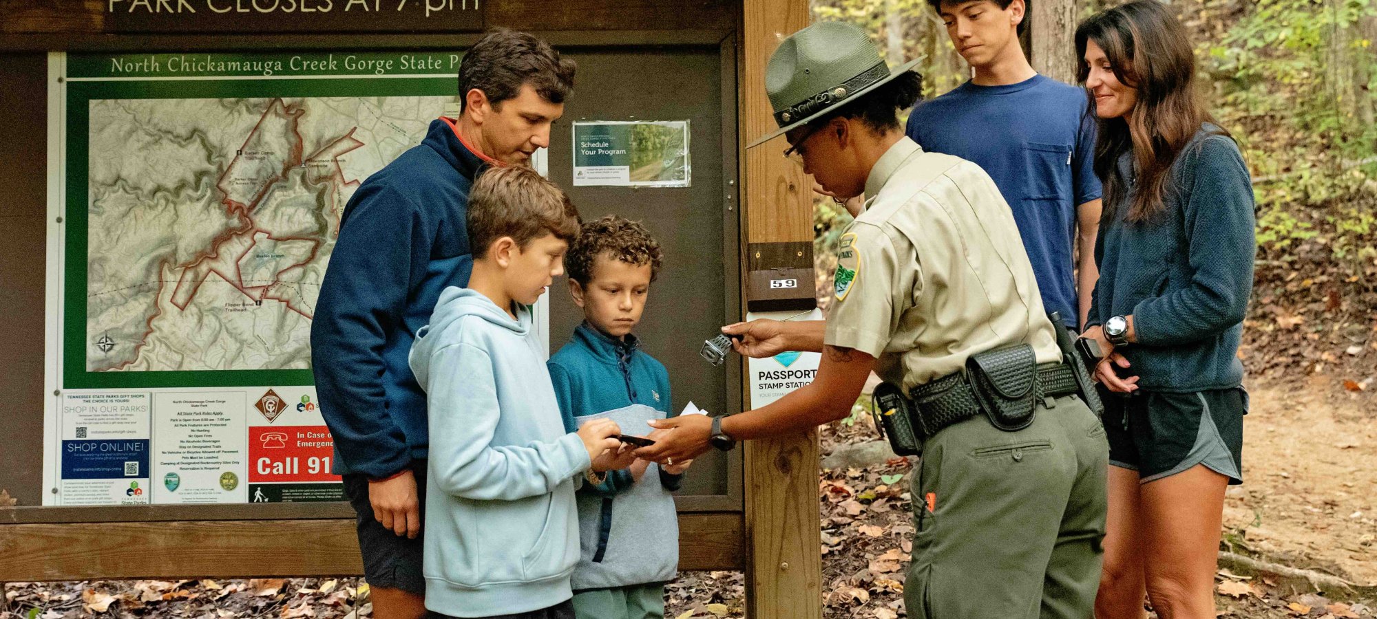ranger with family stamping a book a child is holding