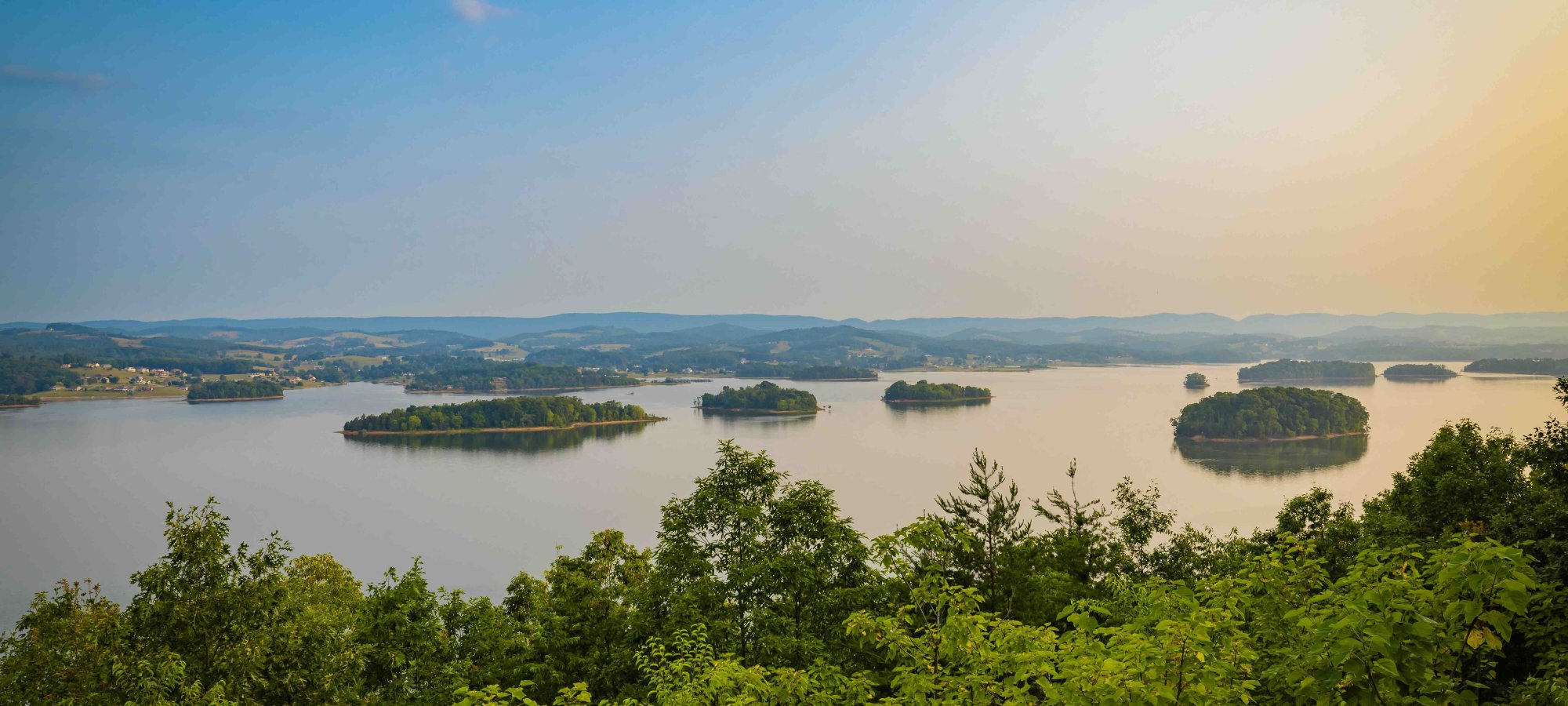 view of multiple small bodies of land on water with the sun beginning to set