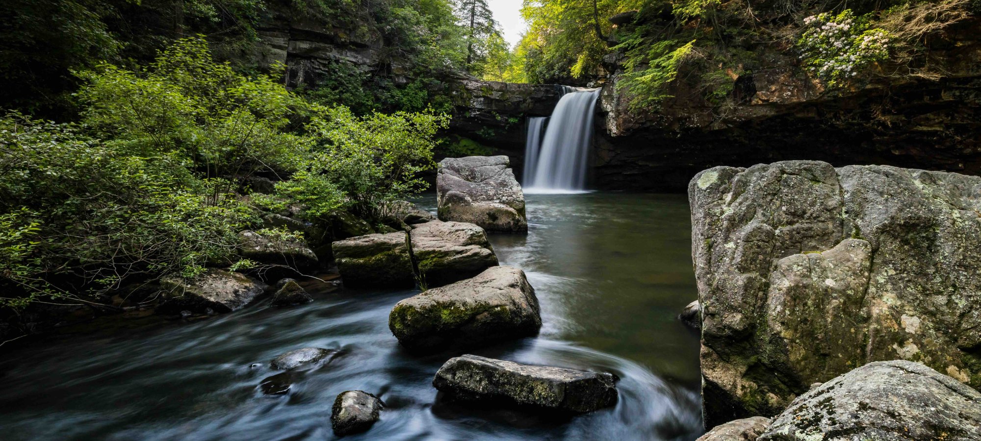 view of rocks and a calm waterfall with small water ripples