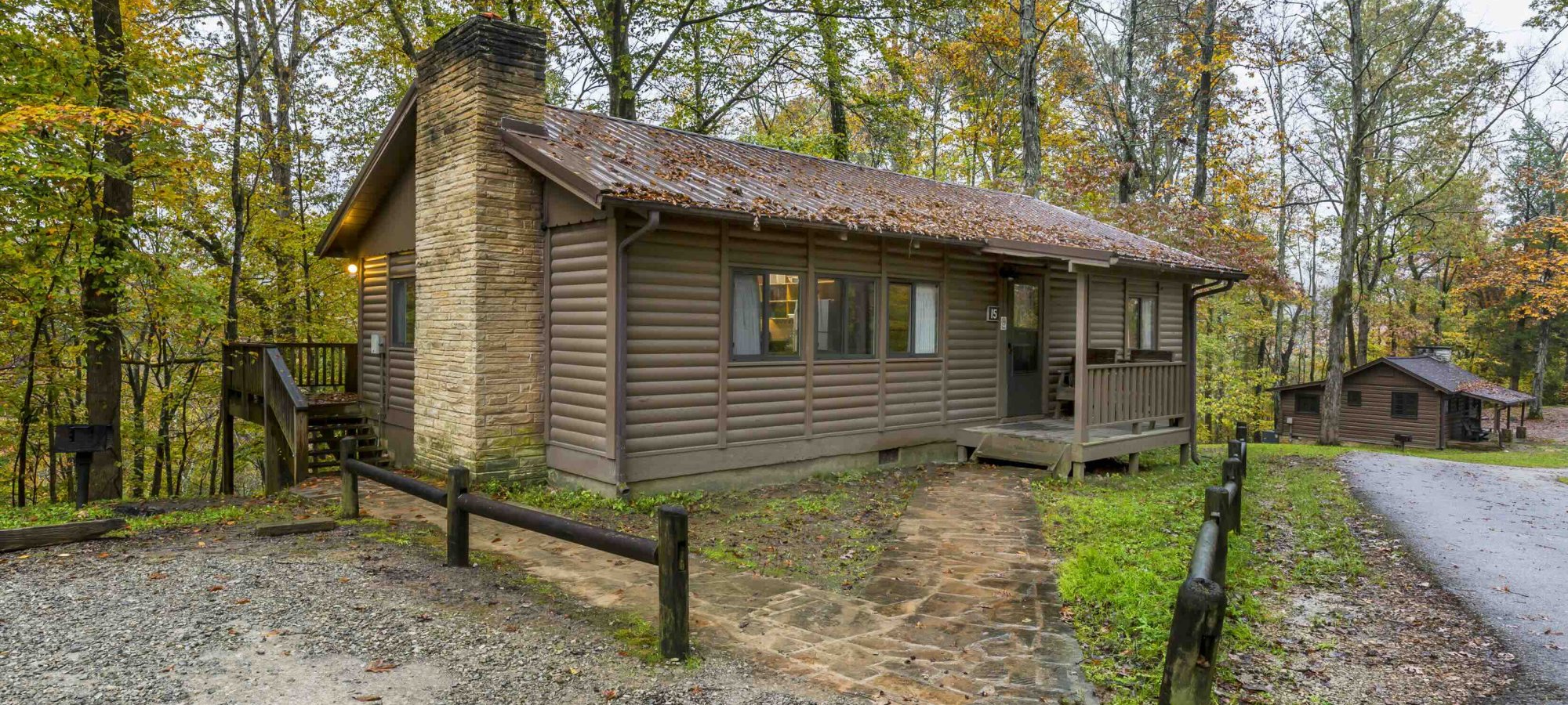 outside of cabin with chimney and leaves on the roof in the spring