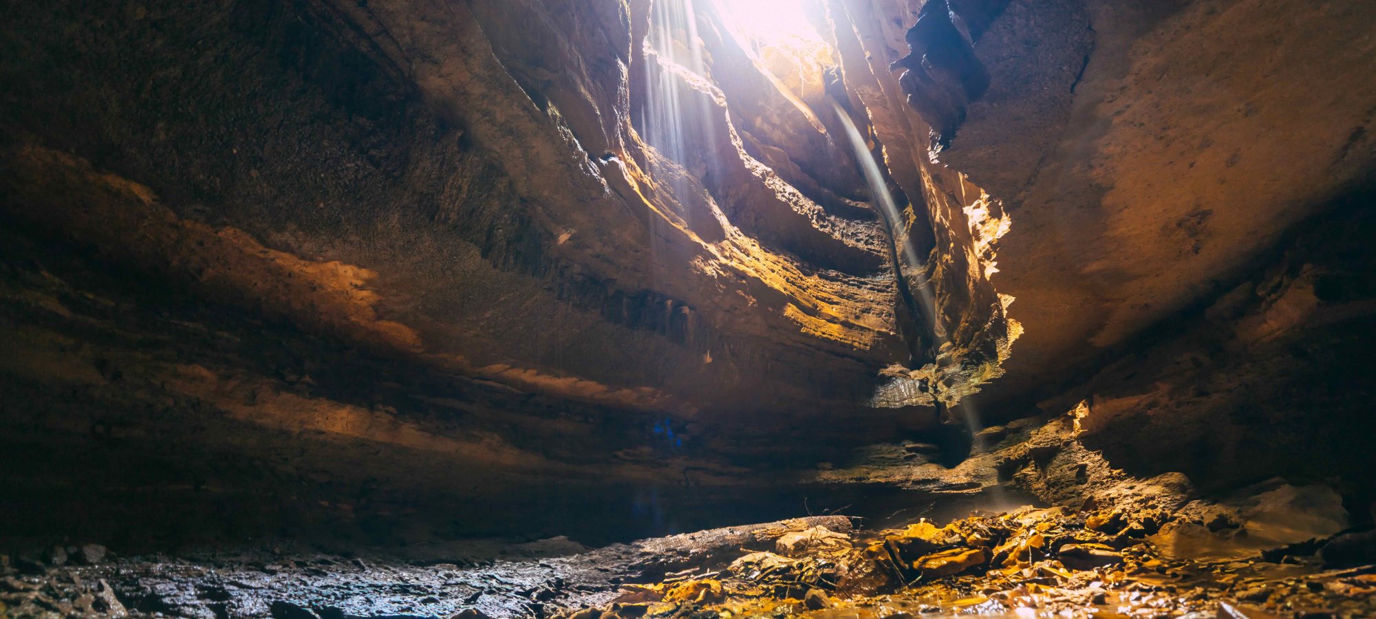 inside cave with hole in the ceiling that has sunlight shining from it