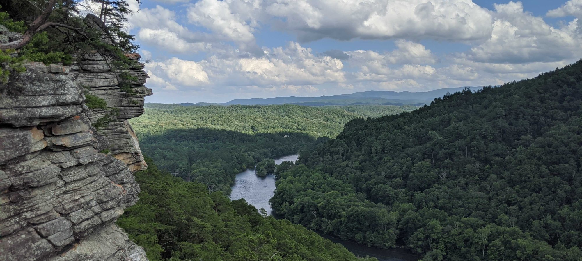 View of landscape with a river, a stone mountain on the left and trees everywhere