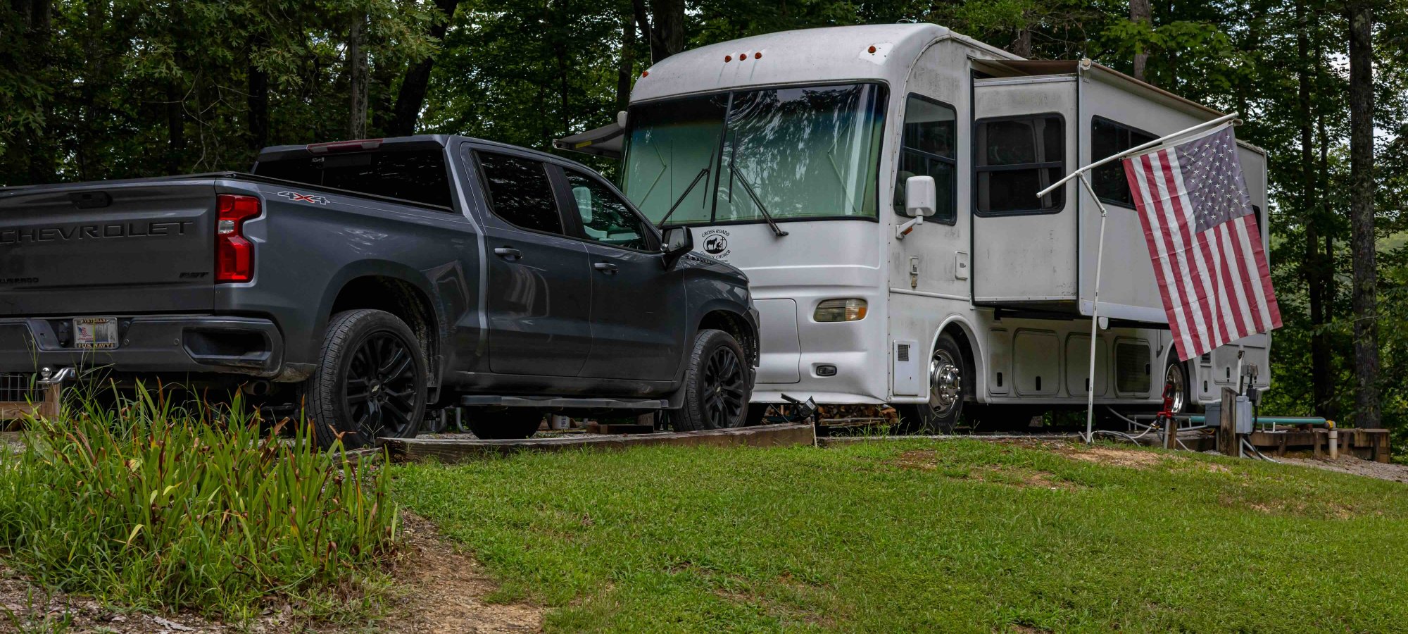 truck parked in front of an RV that is also parked with an American flag on it