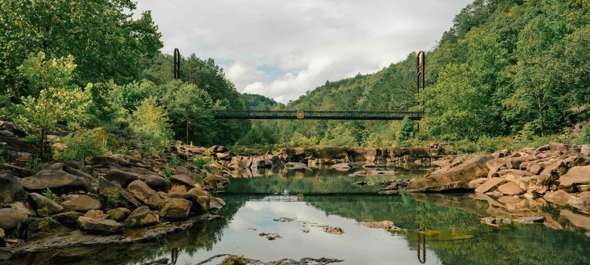 view of river with rocks near the edges and a bridge in the distance