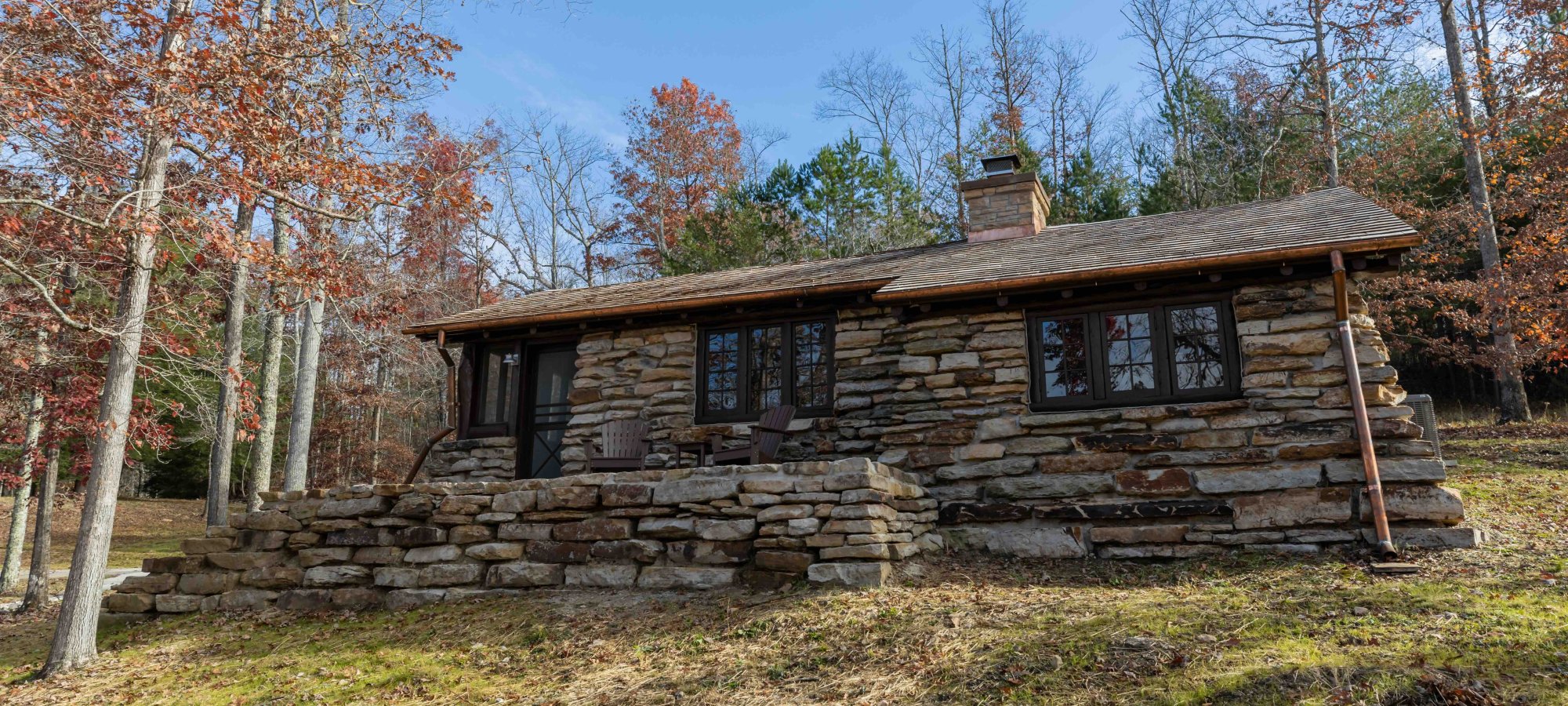 stone cabin with one floor surrounded by trees in the fall
