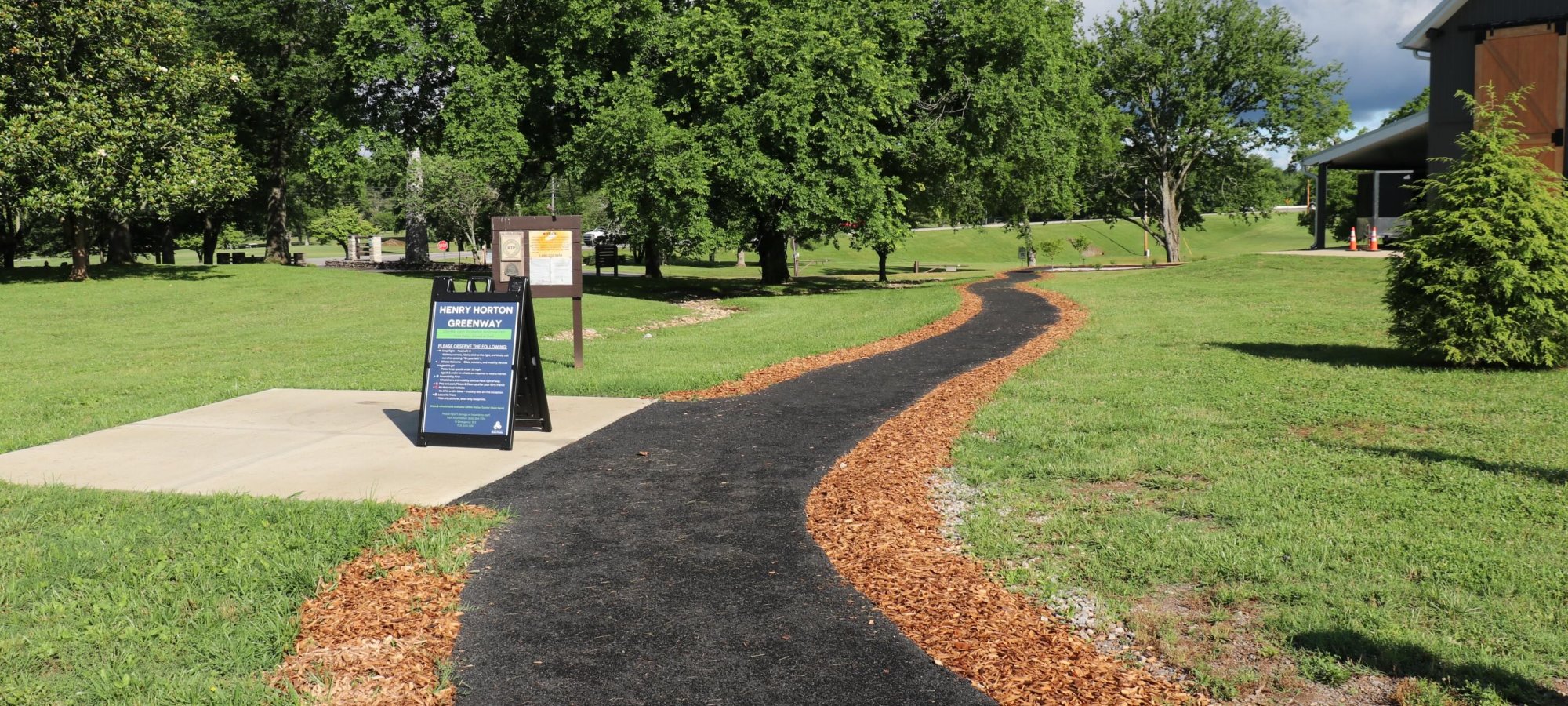 Winding pathway through a lush park with an information board.